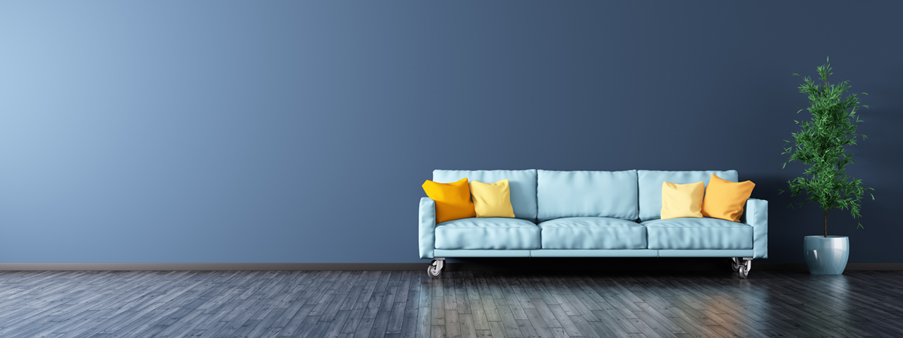 Empty room with wooden floor and wall, featuring a blue sofa.